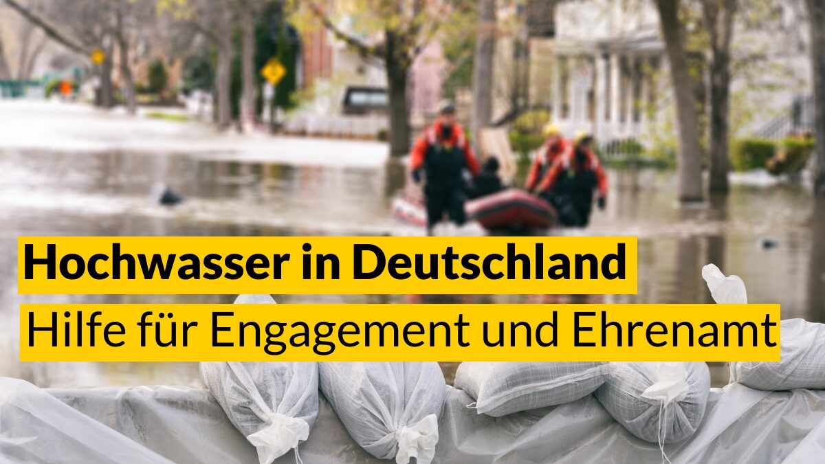 Foto von Sandsäcken als Damm bei einer überfluteten Straße. Text: Hochwasser in Deutschland – Hilfe für Engagement und Ehrenamt