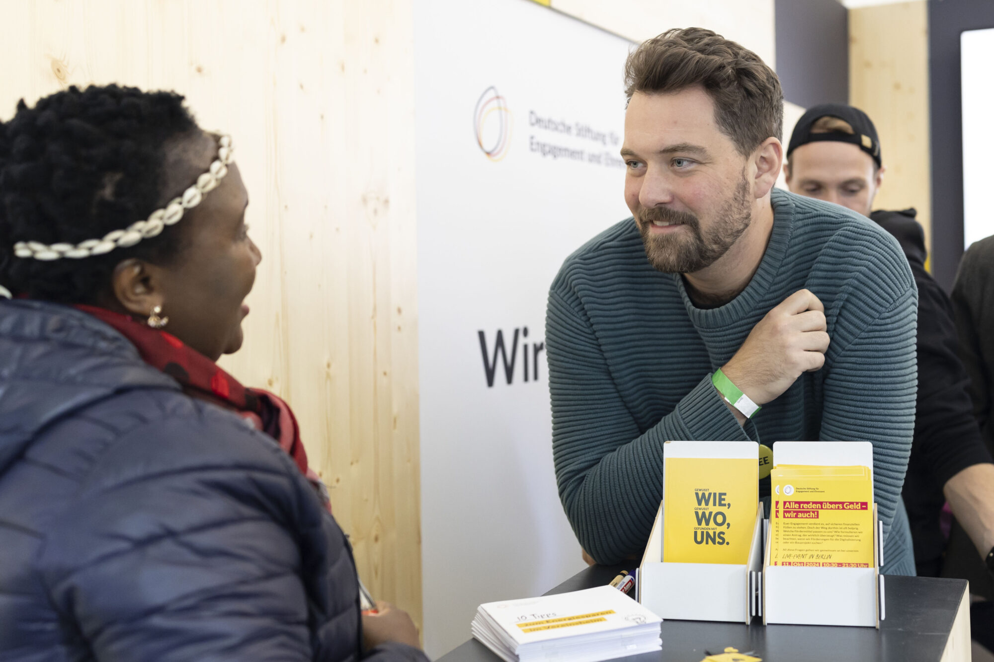 Zwei Menschen an einem Messestand. Eine Person Berät die andere