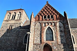 Das Seiteneingangsportal einer Kirche ist zu sehen. Im unteren Bereich ist die Kirche auf Feldsteinen gebaut, im oberen Teil bestimmt Backsteingotik die Bauart