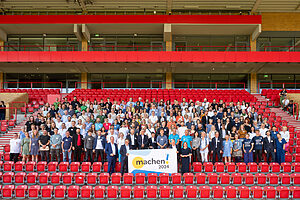 Gruppenbild auf einer Stadiontribüne mit den vielen engagierten Vertretern der Preisträger des Machen!2024 Wettbewerbs.